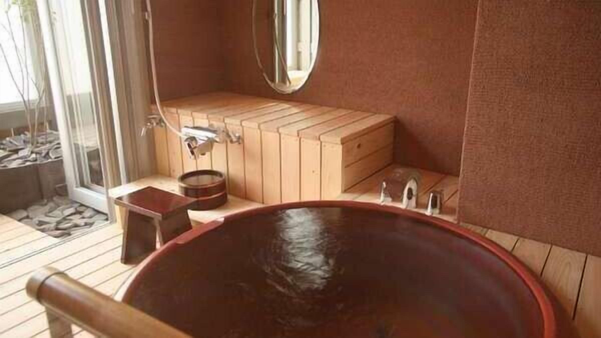 Una sauna de madera con una bañera grande, un banco de madera y un espejo en la pared.