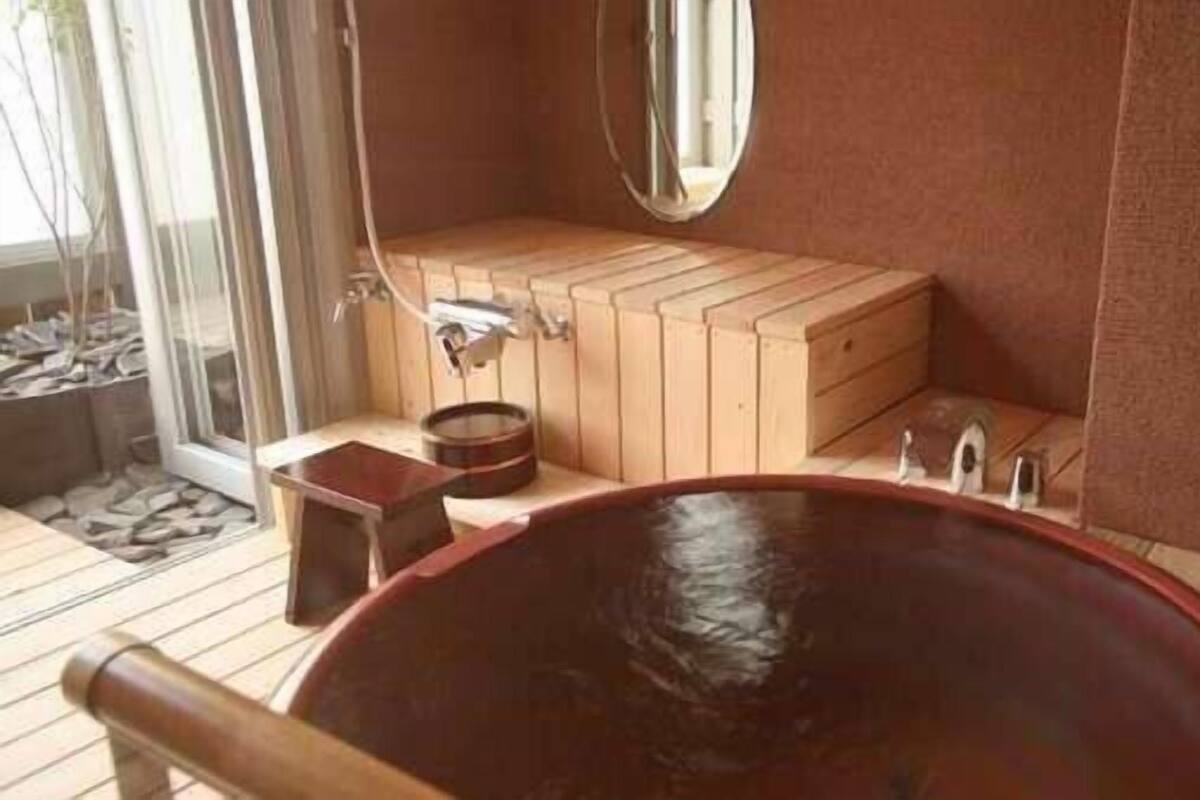 Una sauna de madera con una bañera grande, un banco de madera y un espejo en la pared.