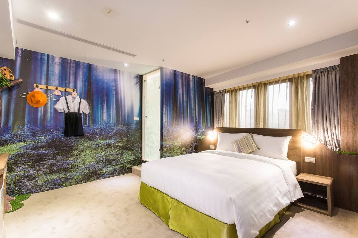 A modern hotel room with a large bed, a nightstand, a wall mural, and a window with curtains.