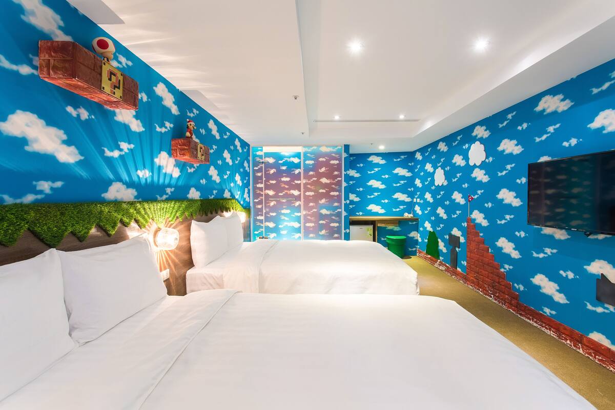 A bedroom with a large bed, a TV, and a mural of clouds on the walls.
