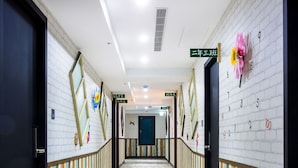 A hotel corridor with wooden flooring, striped walls, and directional signs. - Rf Hotel - Sanchung (New Taipei City)