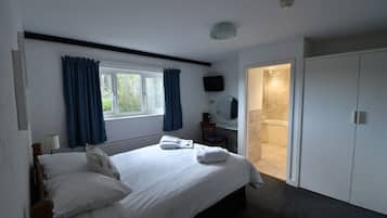Hotellihuone, jossa on sänky, ikkuna verhoilla, televisio, kylpyhuone suihkulla ja vaatekaappi.