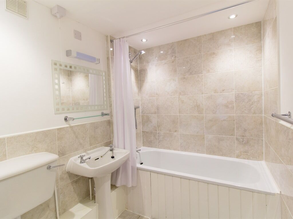 Une salle de bain avec une baignoire, un lavabo et un miroir.