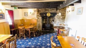Een traditionele pub met houten meubels, een patroon vloer en een stenen muur met een open haard.