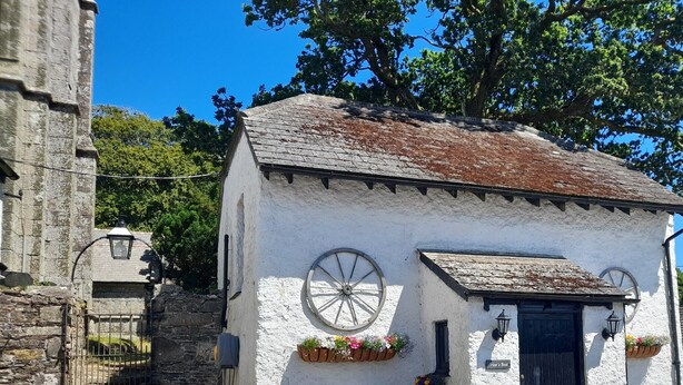 A small white building with a black door, a wheel window, and flower boxes. - The Weary Friar (Saltash)