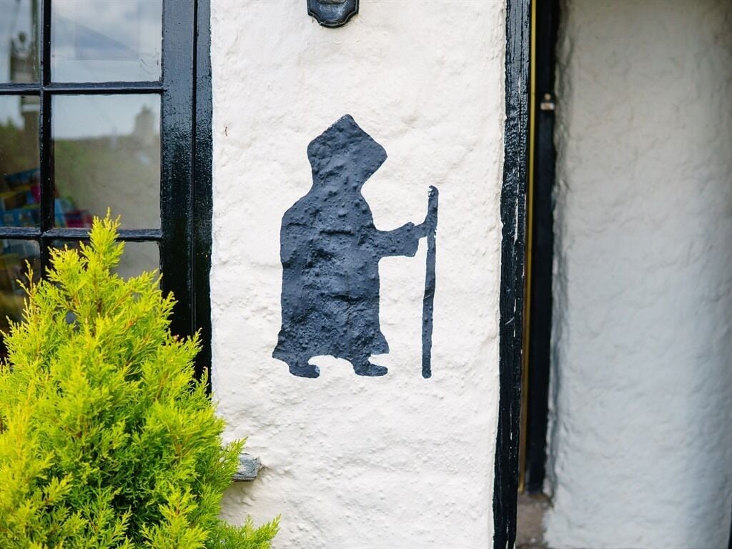A silhouette of a person on a wall, a window, and a bush.