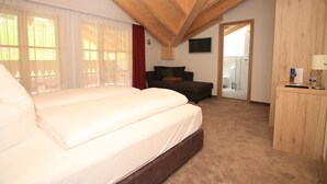Een slaapkamer met een groot bed, een houten plafond, een bank, een televisie en een bureau.
