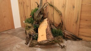Een rustieke houten wand met een decoratieve bloemstuk van takken en groen.