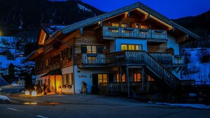 Een meerlaags hotel met een balkon op de tweede verdieping, een trap aan de rechterkant en een bord met de tekst 'AlpinHotel'.