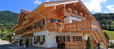 Una cabaña de madera con varios balcones, grandes ventanales y una escalera que lleva al piso superior.