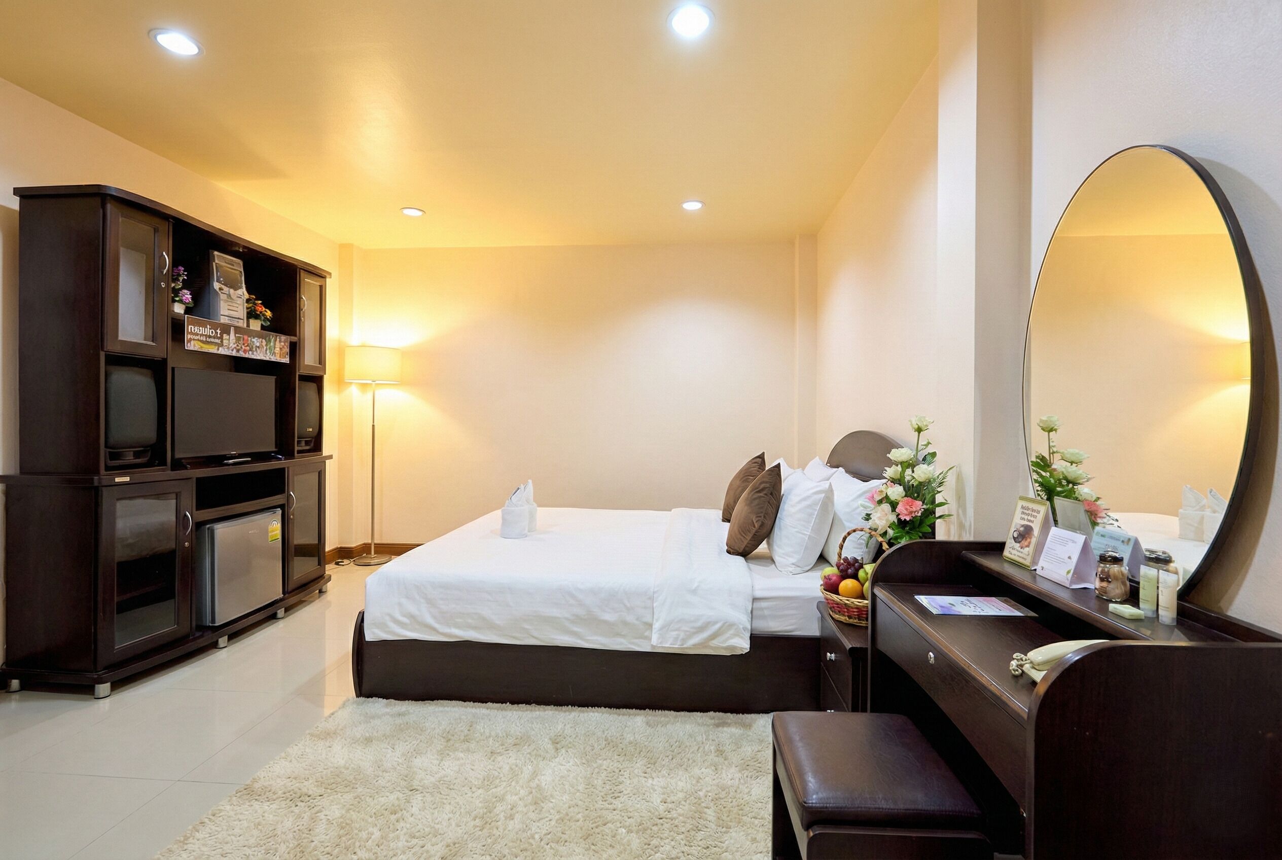 A hotel room with a bed, a desk, a mirror, a wardrobe, and a lamp.
