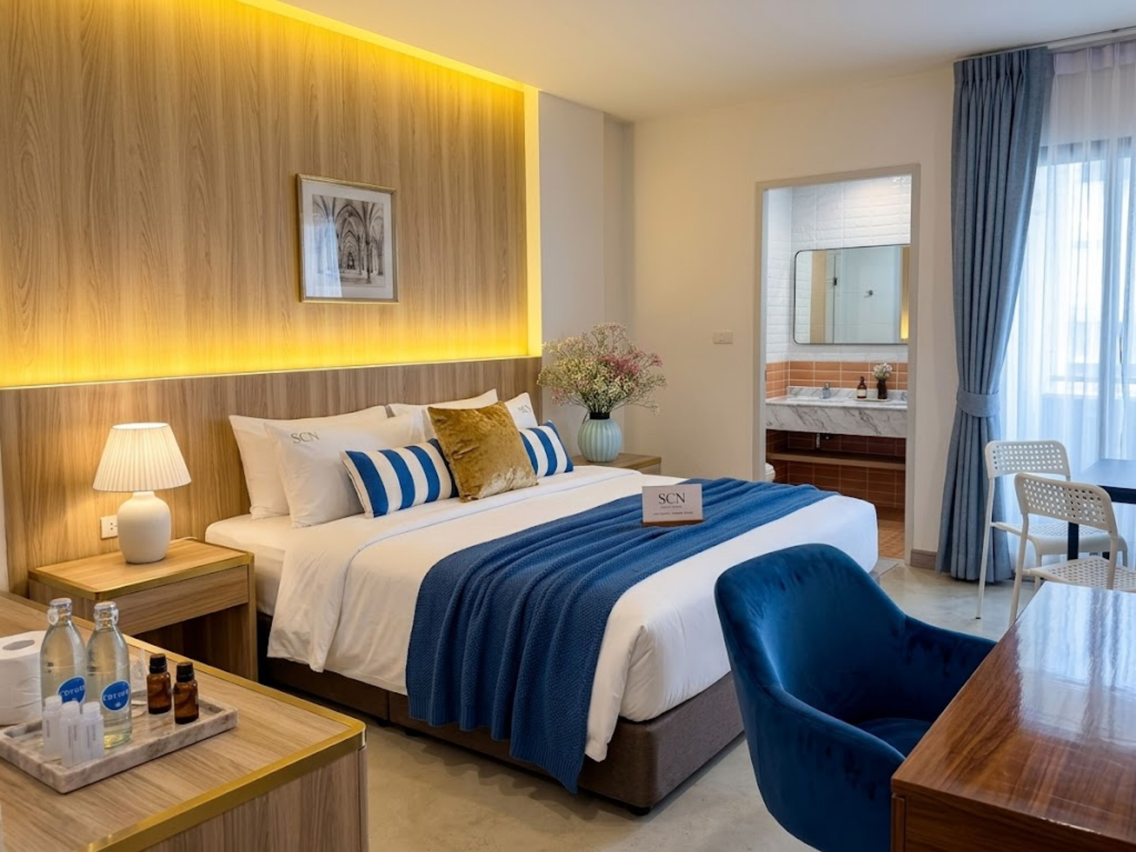 Una habitación de hotel con cama, mesita de noche, lámpara y escritorio con silla.