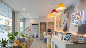 Een hotel receptie in modern design, met een receptiebalie, een zithoek en een grote wand met de naam van het hotel.
