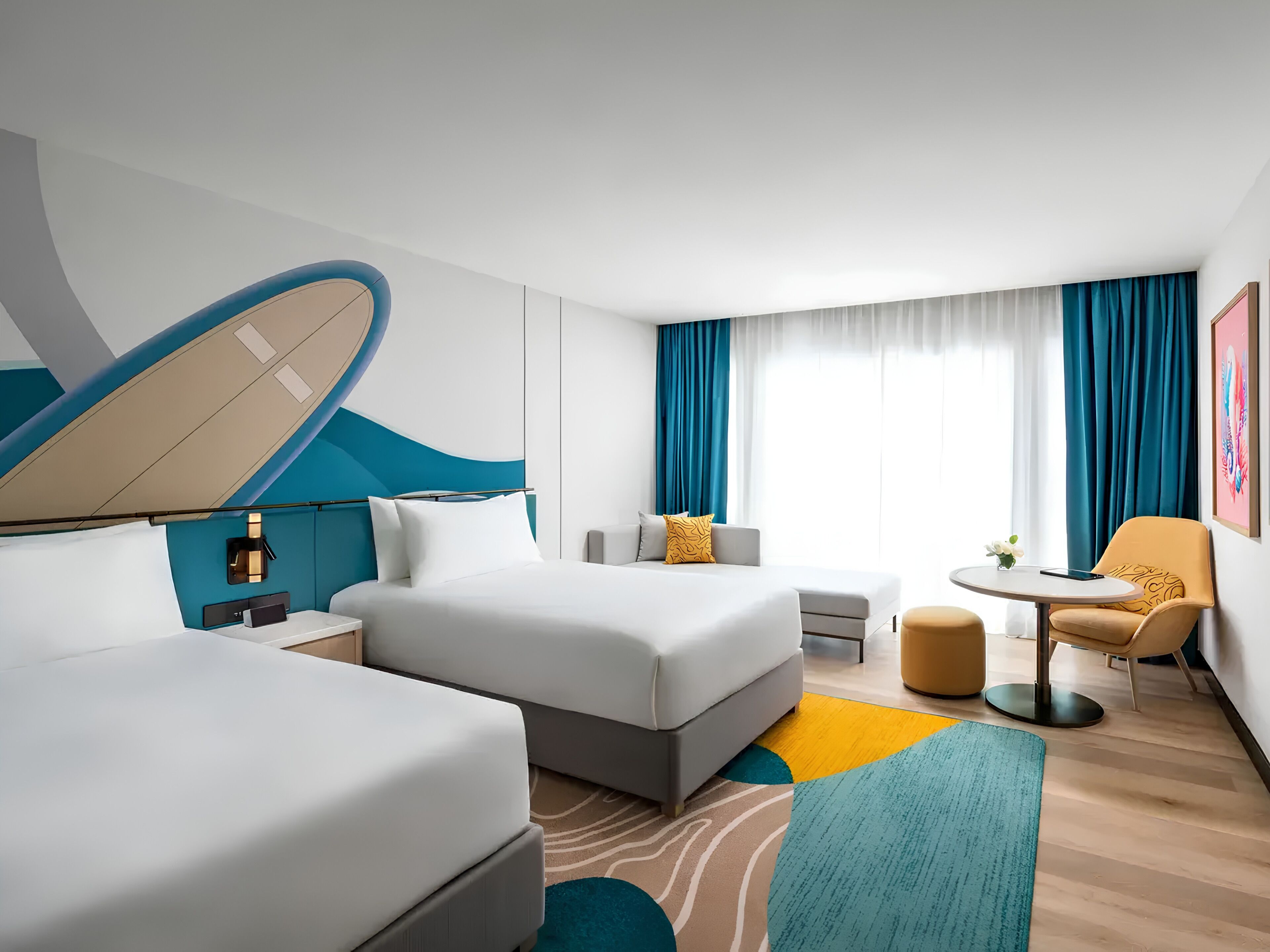 A hotel room with two beds, a small table, a chair, a sofa, and a large window with curtains.