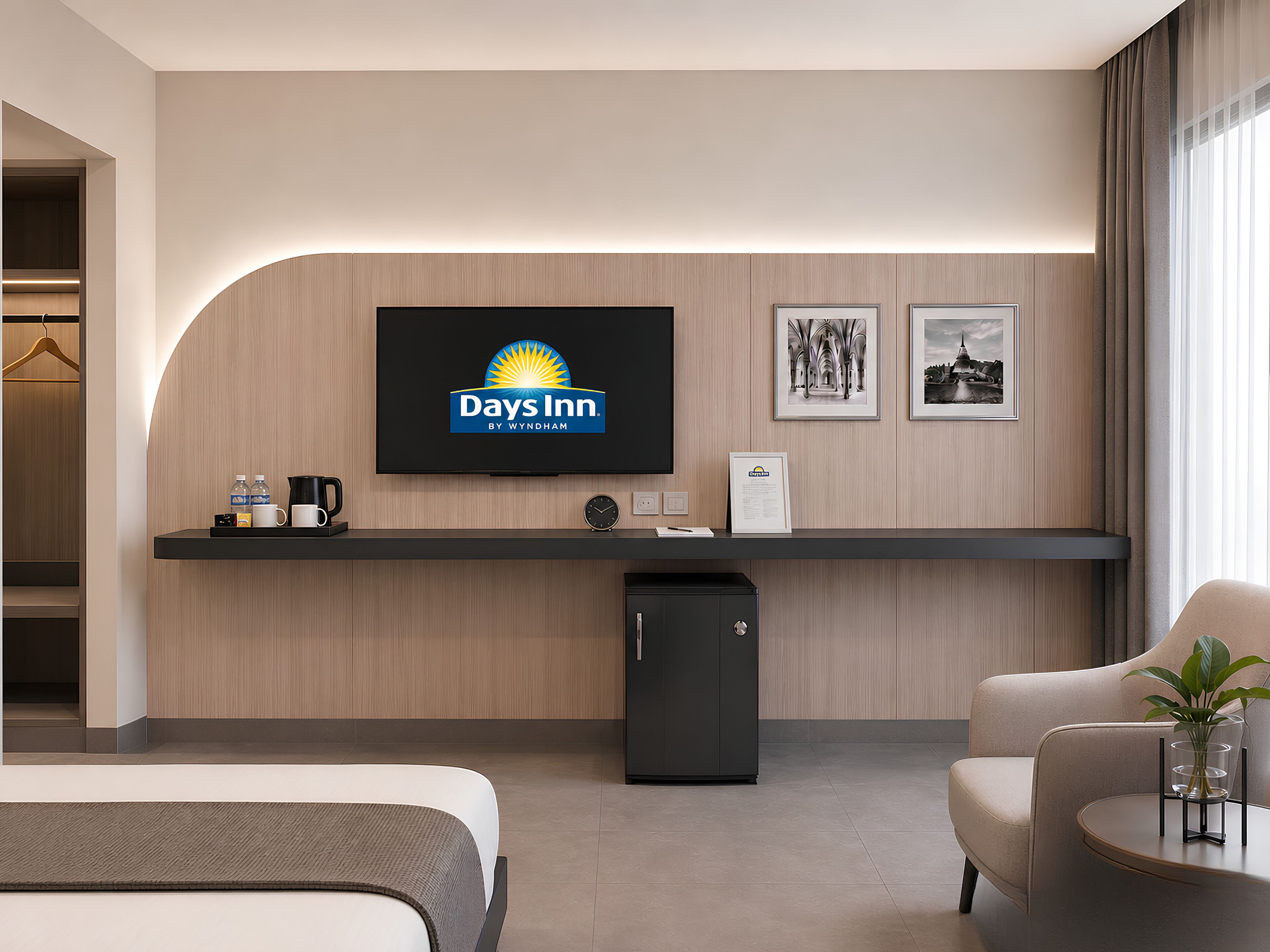 Een hotel receptie met een flatscreen televisie waarop het Days Inn logo staat, een receptiebalie, een kleine koelkast en een zithoek met een plant.