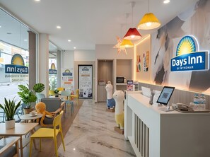 Ein Empfangsbereich eines Days Inn Hotels mit modernem Design, inklusive Rezeption, Sitzgelegenheiten und Dekorationselementen.