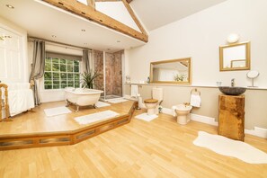 A spacious bathroom with a freestanding bathtub, a large mirror, and a wooden floor. - Cornerstones, 16th Century Luxury Self Catering House overlooking the River Dee (Llangollen)