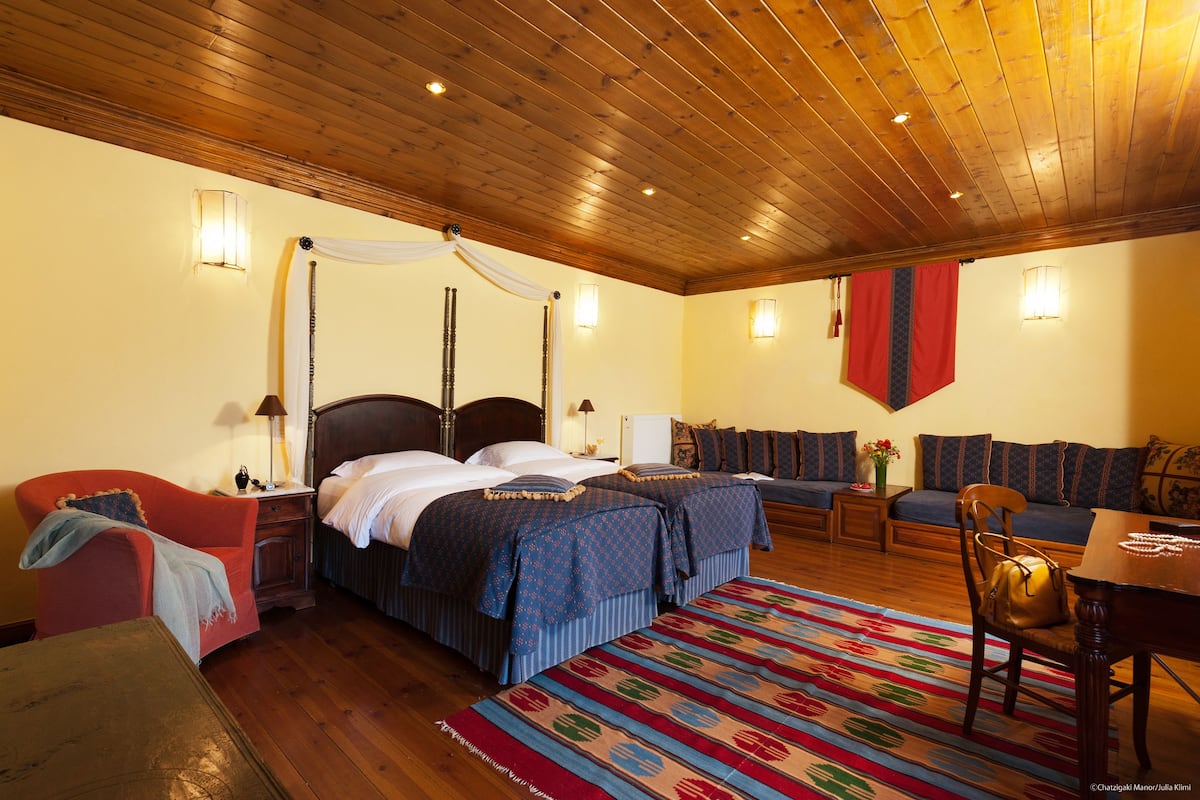 Ein Zimmer mit Holzboden, einem Himmelsbett, einer Couch, einem Sessel und einem Tisch mit Lampe.
