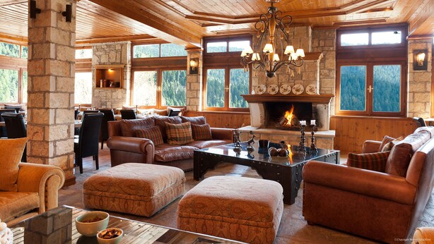 A cozy living room with a fireplace, stone pillars, and wooden furniture. - The Chatzigaki Manor (Pyli)