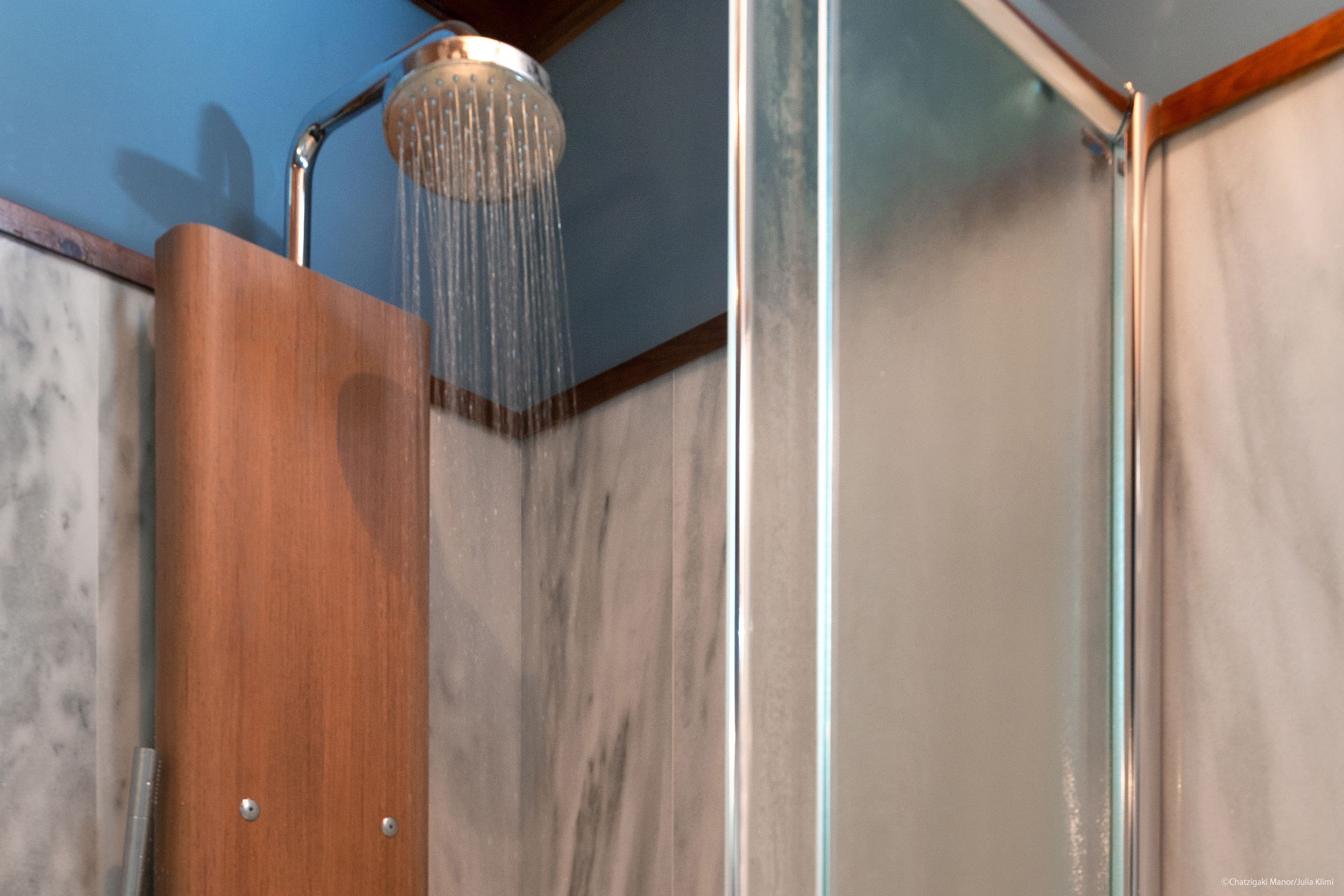 A shower with a wooden panel and a glass enclosure.