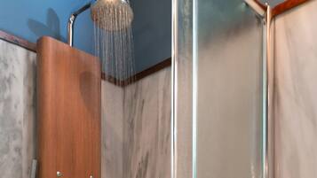 A shower with a wooden panel and a glass enclosure.