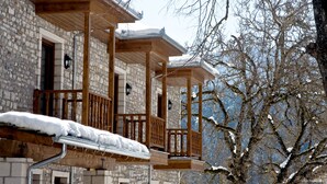 A stone building with wooden balconies and snow-covered roofs. - The Chatzigaki Manor (Pyli)