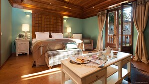 A cozy bedroom with a bed, bedside tables, a desk with breakfast items, and a view through a window. - The Chatzigaki Manor (Pyli)