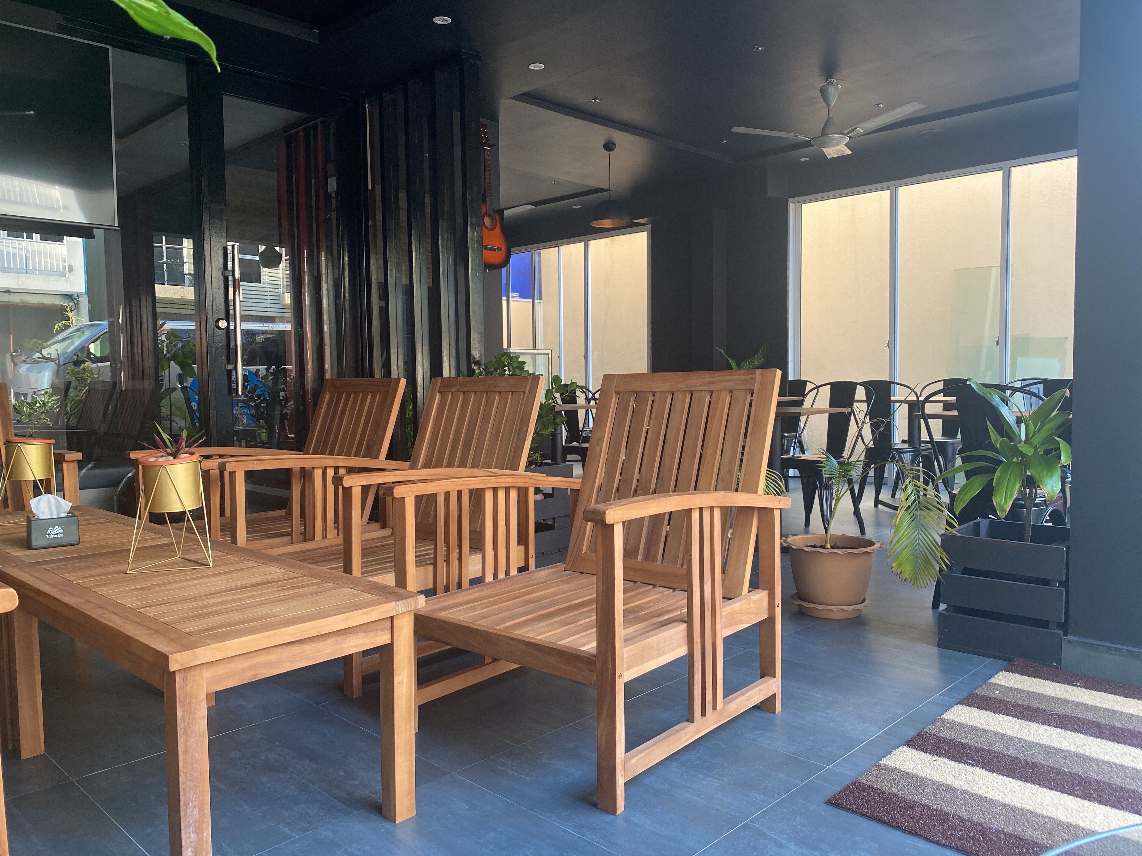 Un espacio exterior moderno con mobiliario de madera y plantas en macetas.
