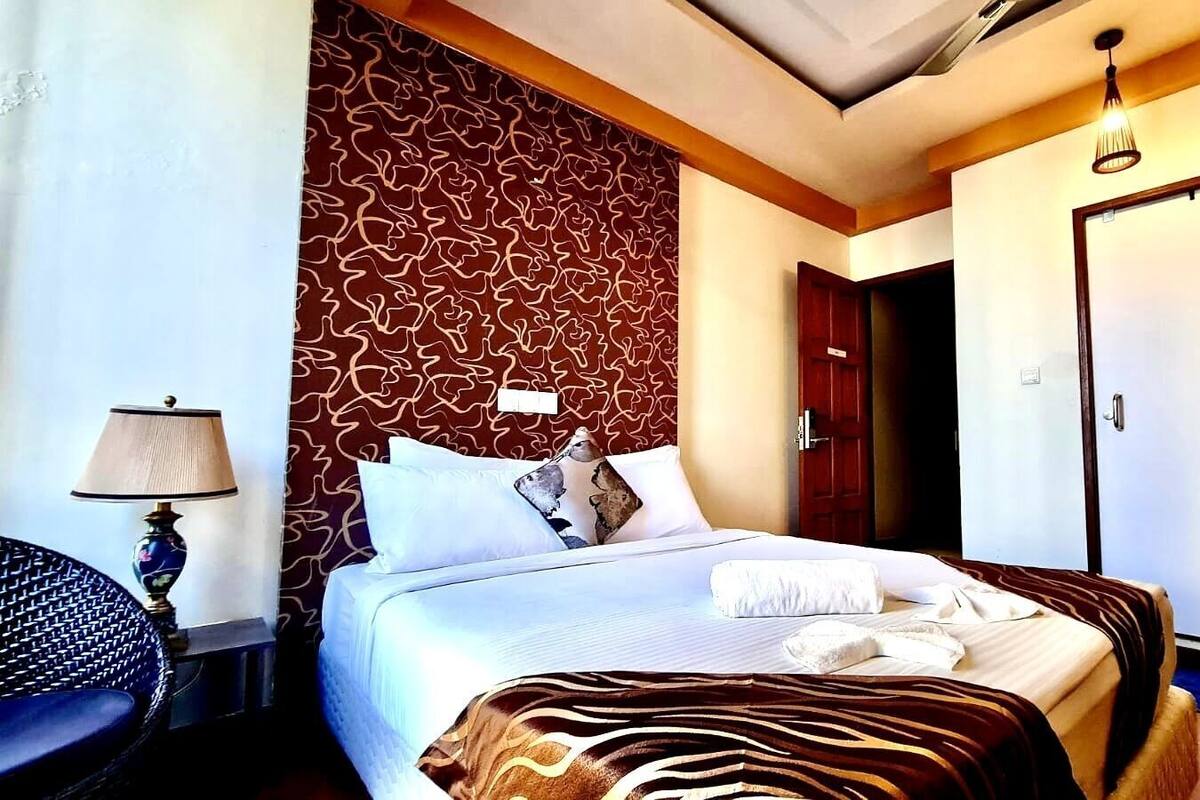 A hotel room with a bed, a bedside lamp, a wardrobe, and a door.