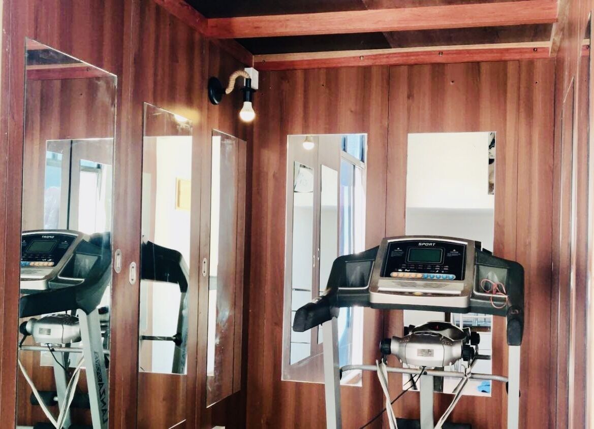 A room with wooden walls and mirrored doors, a treadmill, and a stationary bike.