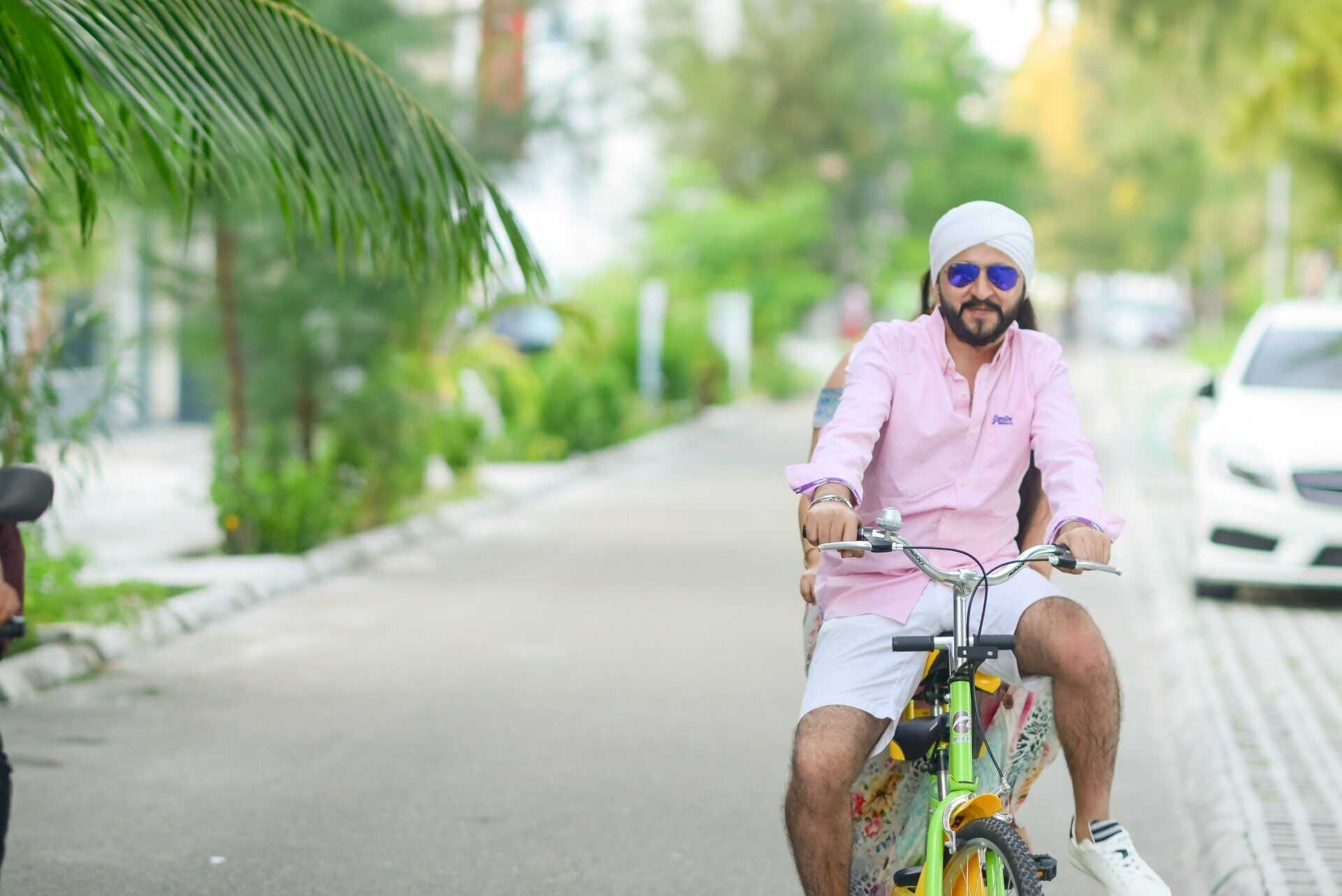 A person riding a bicycle on a paved road with greenery on the sides.