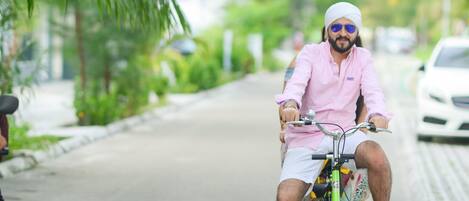 A person riding a bicycle on a paved road with greenery on the sides.