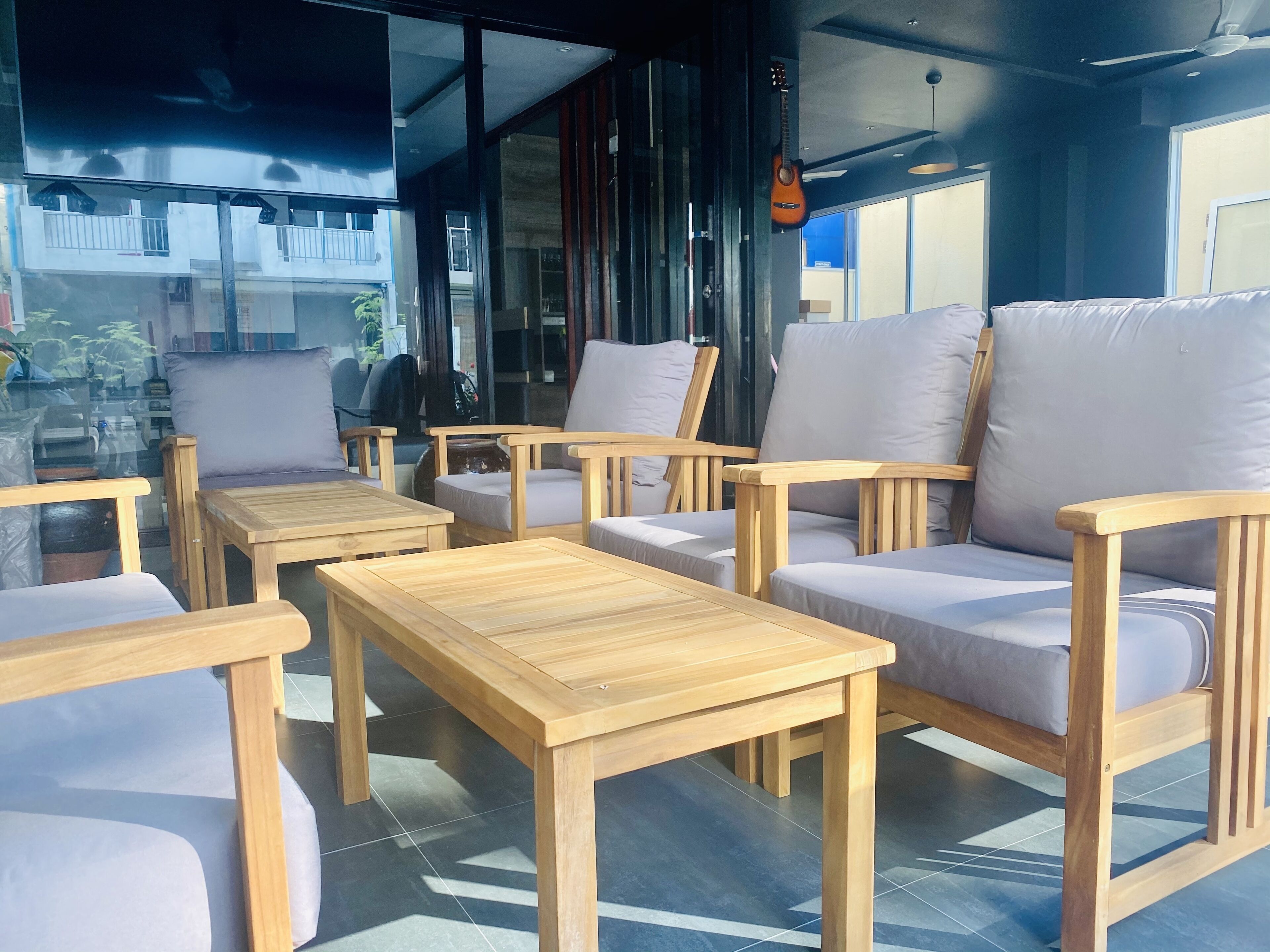 Un intérieur moderne avec des meubles en bois, notamment des canapés et des tables, et de grandes fenêtres offrant une vue sur l’extérieur.