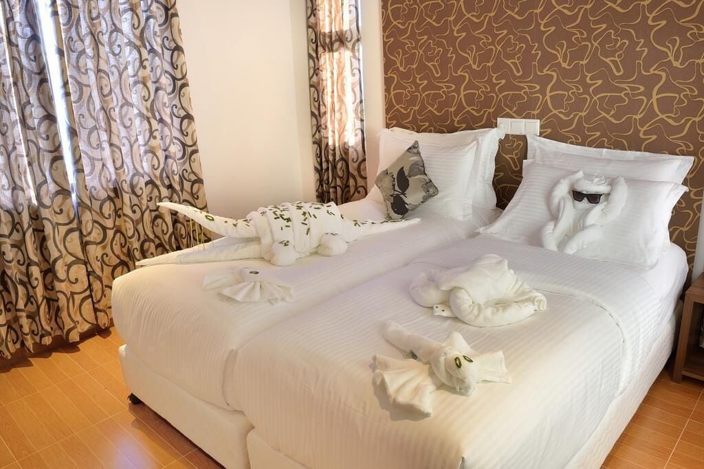 Una camera d'albergo con un letto grande, biancheria da letto bianca e cuscini decorativi.