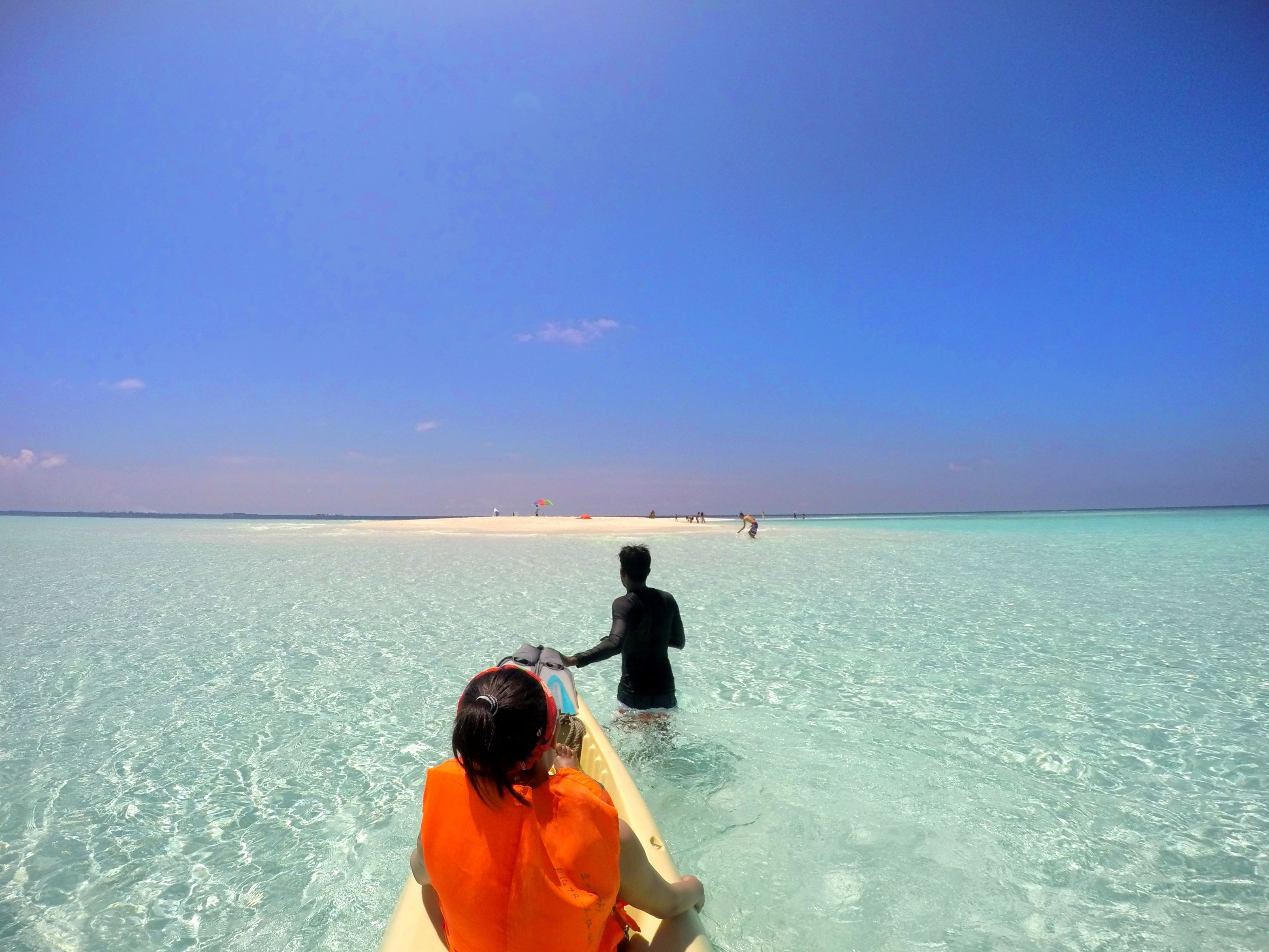 On voit clairement une plage et une personne qui rame sur un canoë.