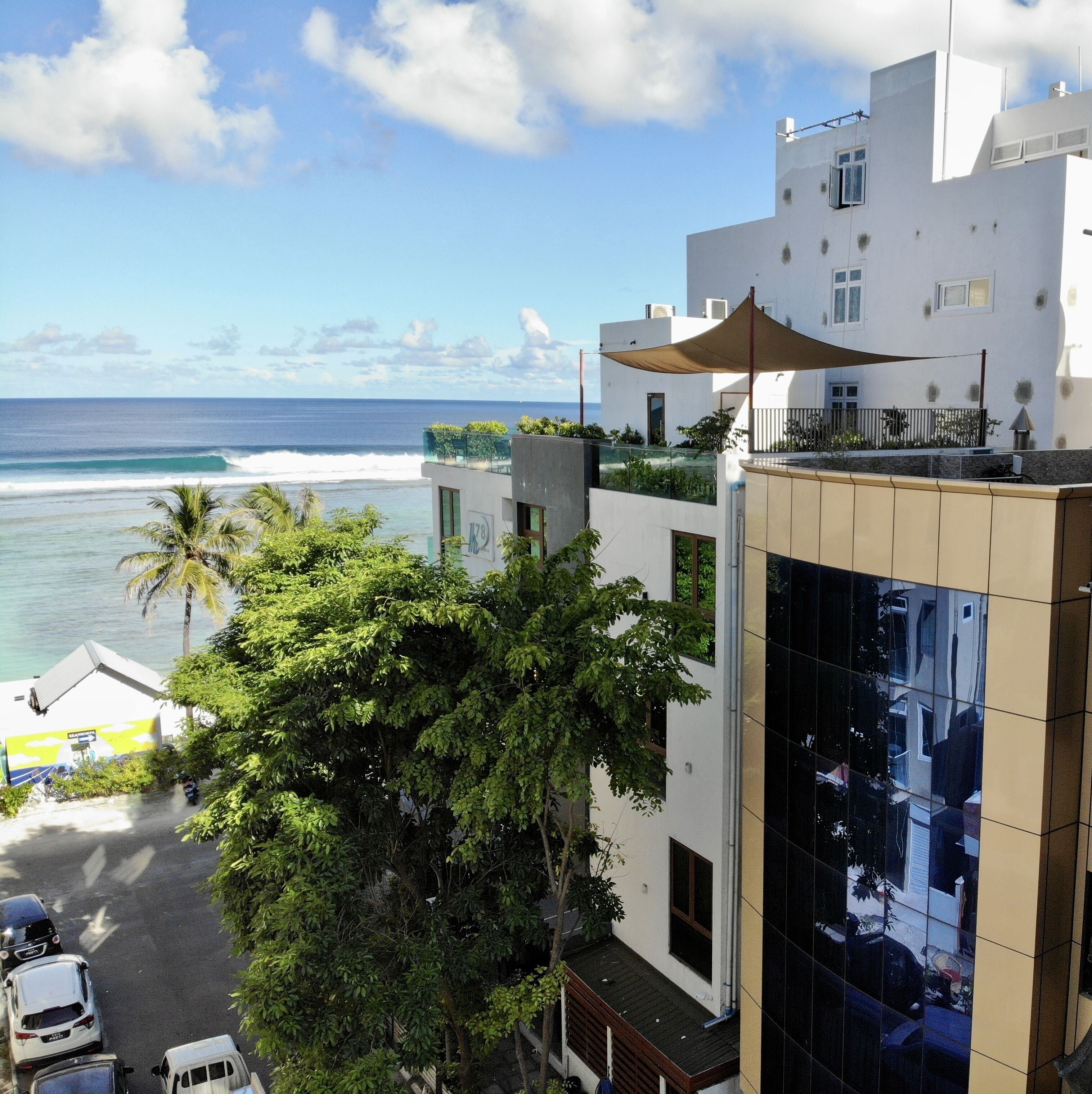 A modern building with a balcony overlooking a beach and ocean.