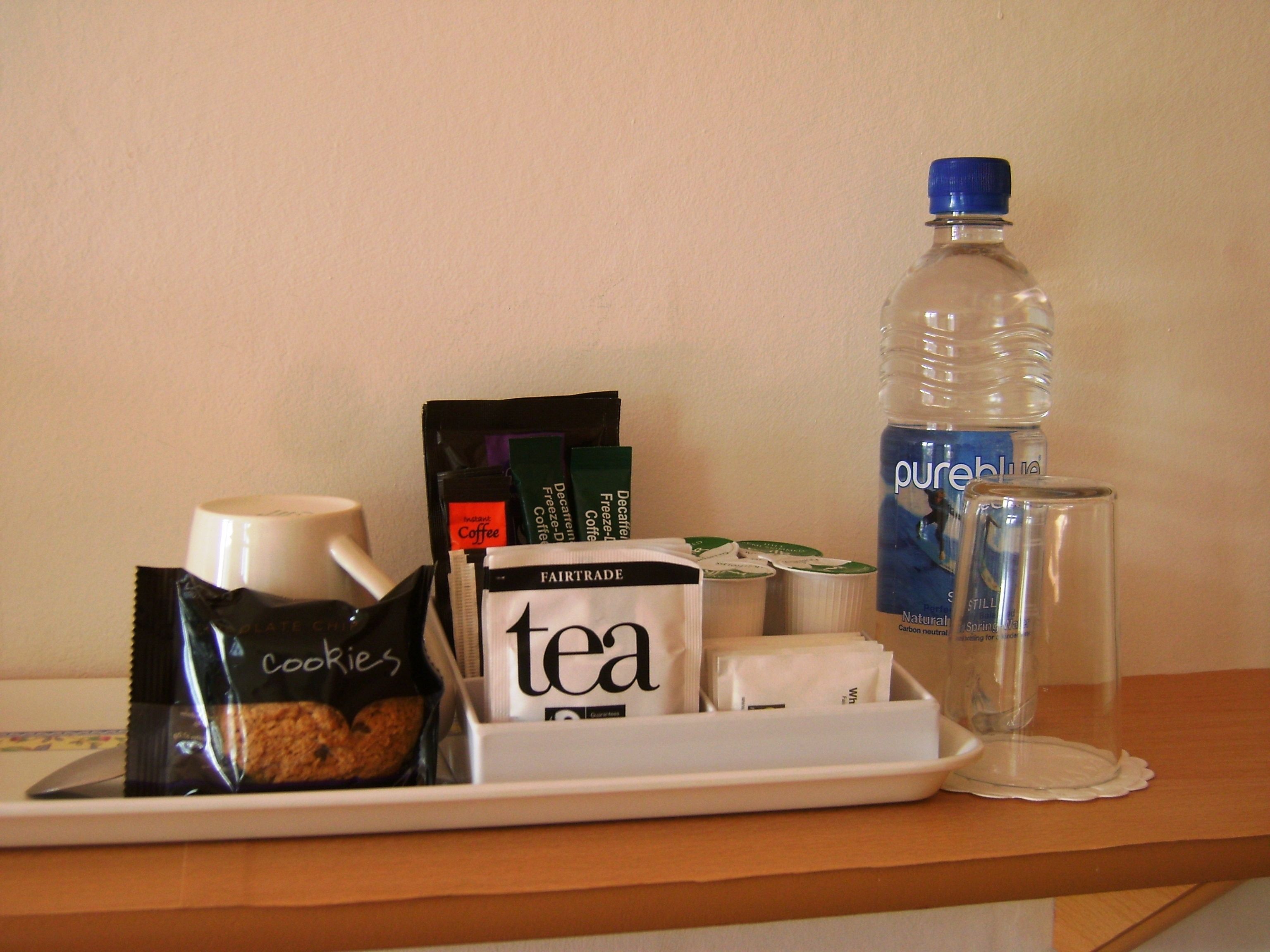 A tray with a coffee cup, tea bag, cookies, and a bottle of water.