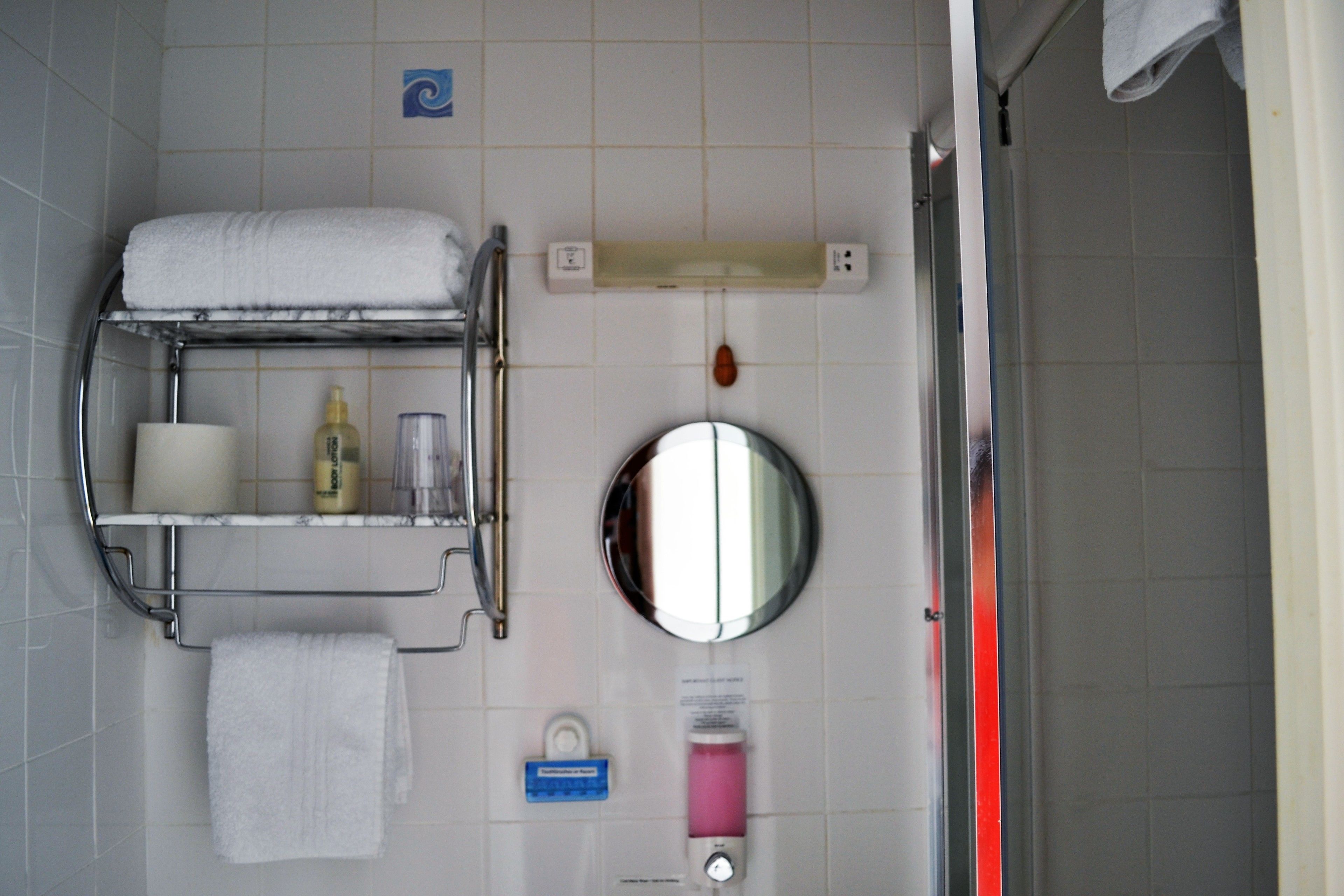 A bathroom with a towel rack, a mirror, a soap dispenser, and a hand dryer.