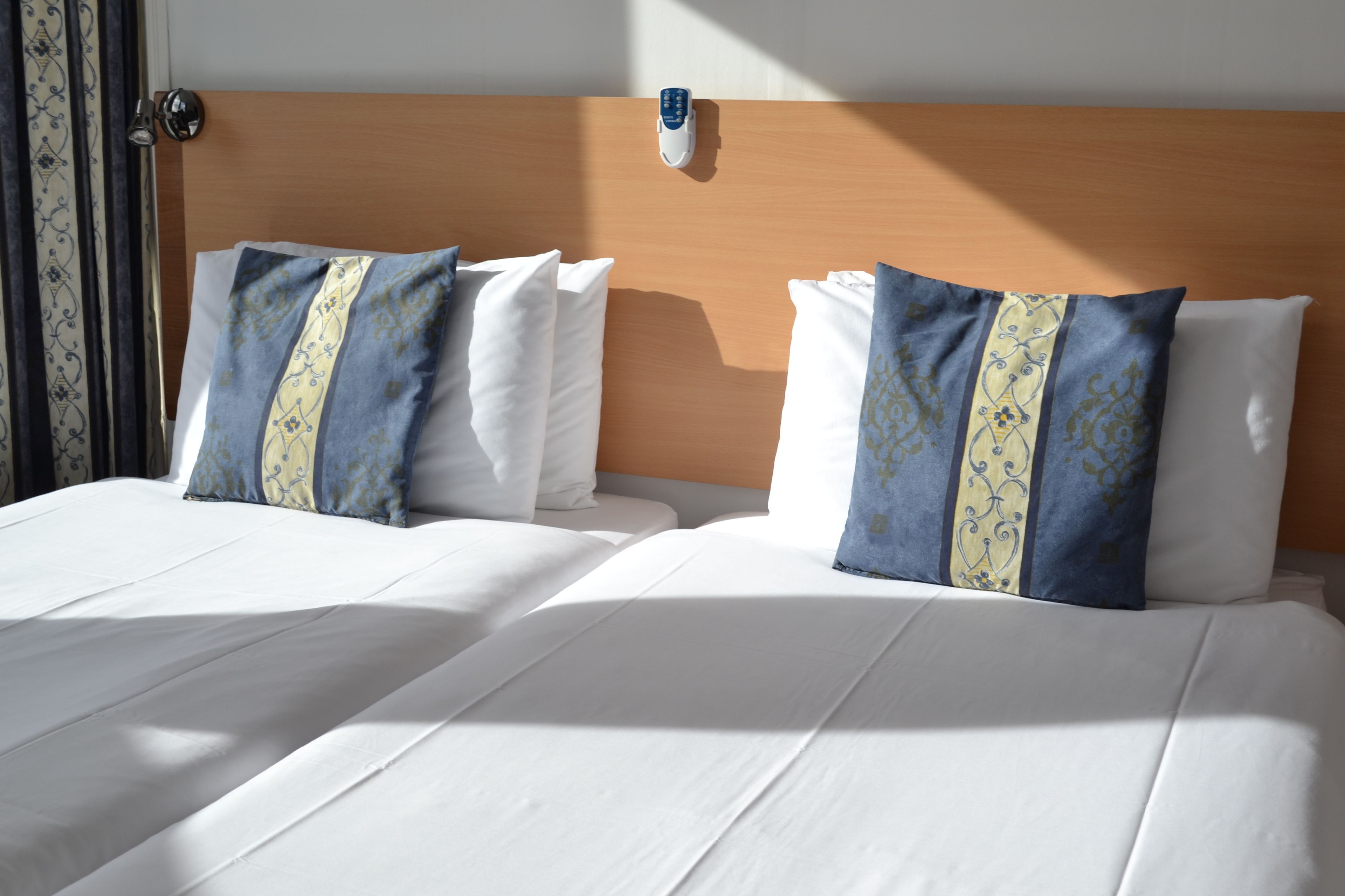 Una habitación de hotel con dos camas, cada una con sábanas blancas y almohadas decorativas.