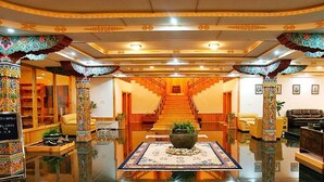 Eine Lobby mit einer zentralen Treppe, aufwendigen Säulen und einer Rezeption.