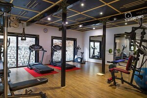 Un gimnasio con cintas de correr, bicicletas estáticas y equipo de levantamiento de pesas.