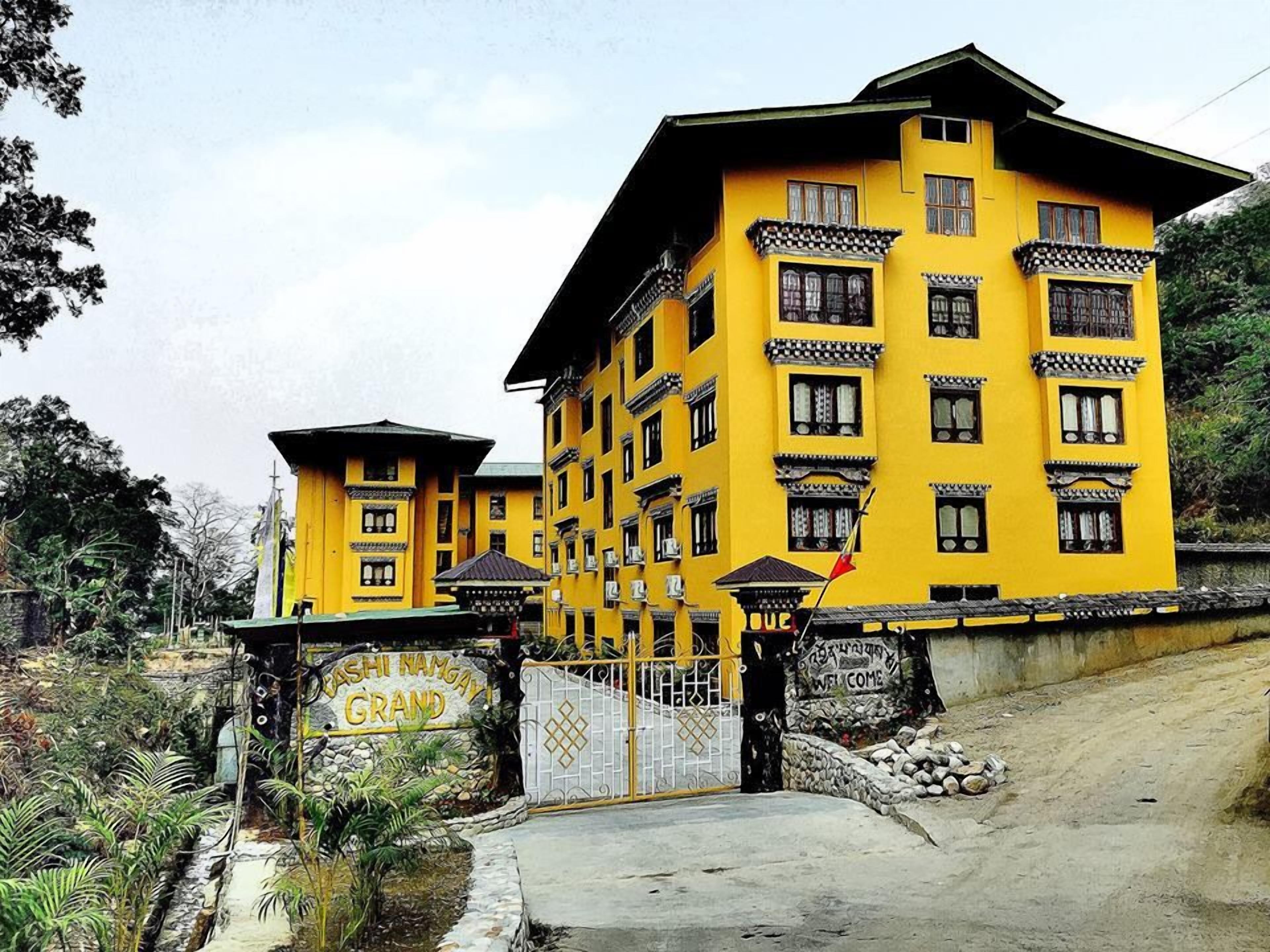 A yellow building with multiple windows and a sign that reads "CASHI NAMAY GRAND".