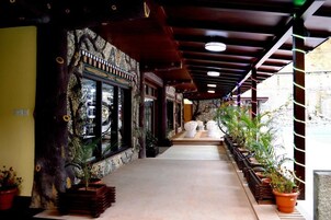 Un pasillo con pared de piedra, vigas de madera y plantas en macetas.
