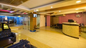 Um saguão de hotel com balcão de recepção, área de estar e bar.