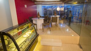 Restaurante com vitrine de vidro, área de estar e parede com padrão vermelho.