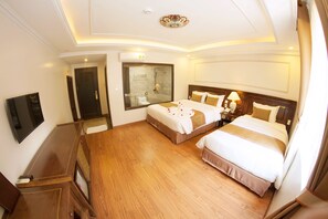 Habitación de hotel con dos camas, televisión, escritorio y zona de ducha.