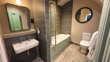 A modern bathroom with a sink, mirror, shower, and toilet.