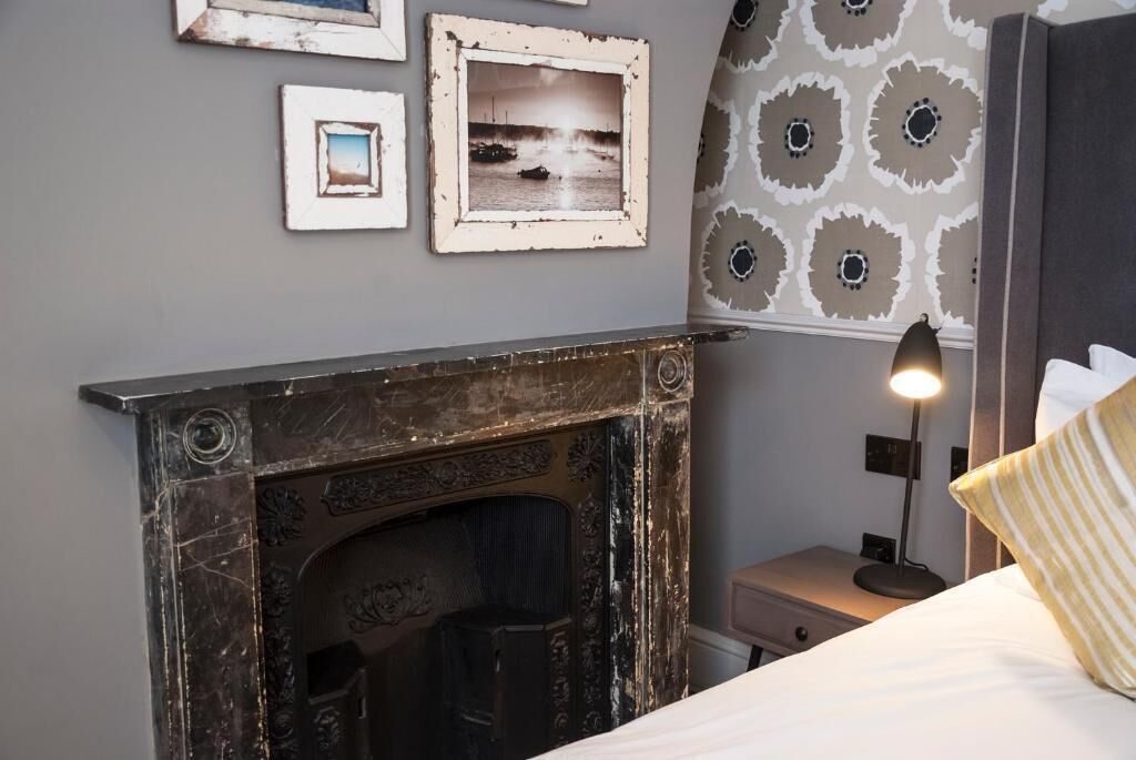 A bedroom with a fireplace, a bed, a nightstand, and wall-mounted pictures.