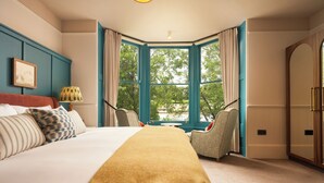 A bedroom with a large bed, a window with curtains, a chair, and a bedside table. - Mill on the Exe (Exeter)