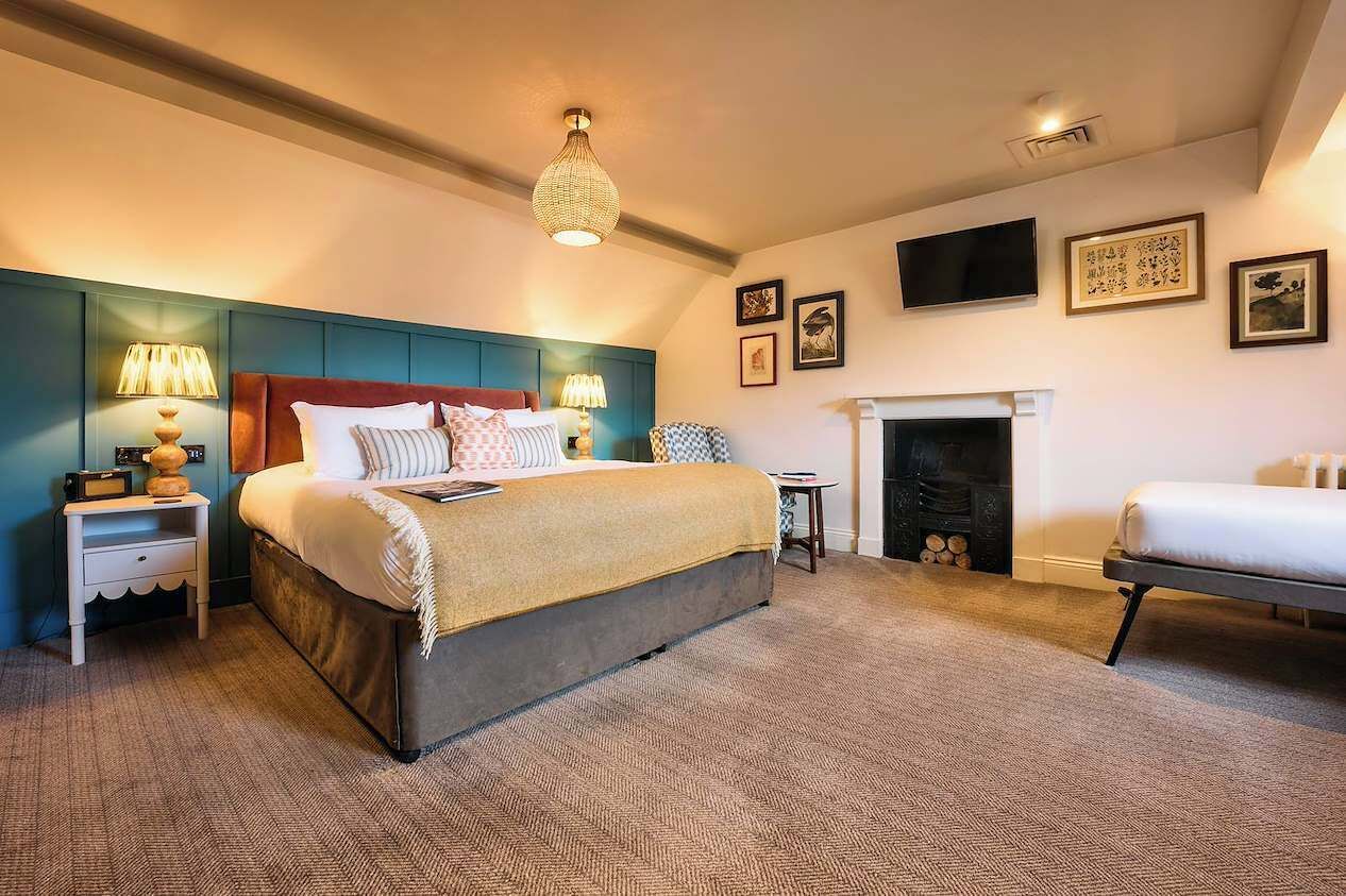 A bedroom with a large bed, bedside tables, a fireplace, and wall-mounted artwork.